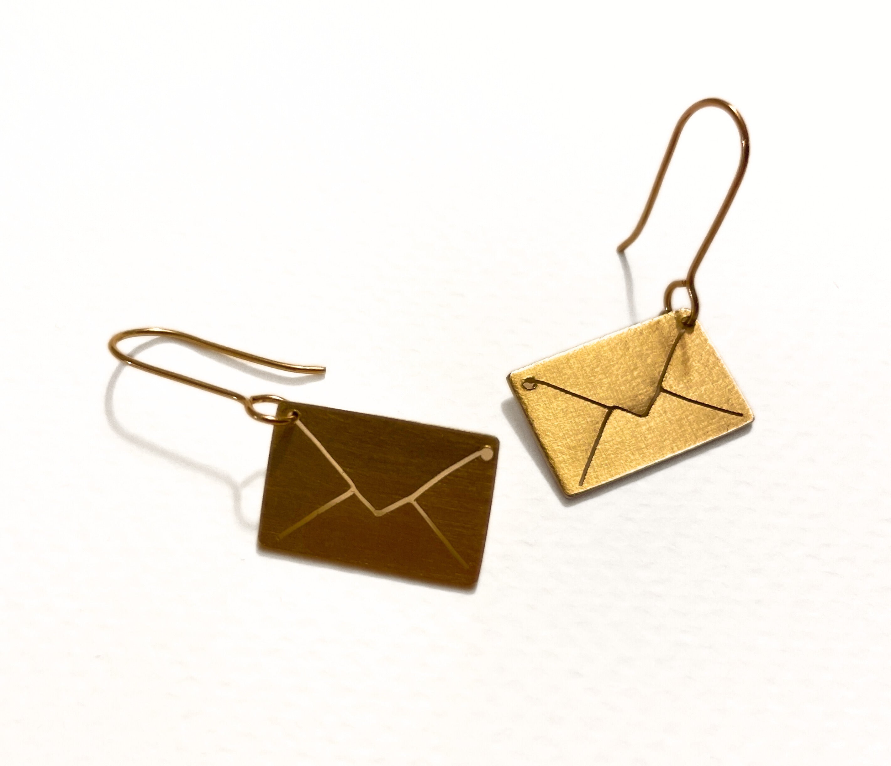 Gold envelope-shaped earrings on a white background
