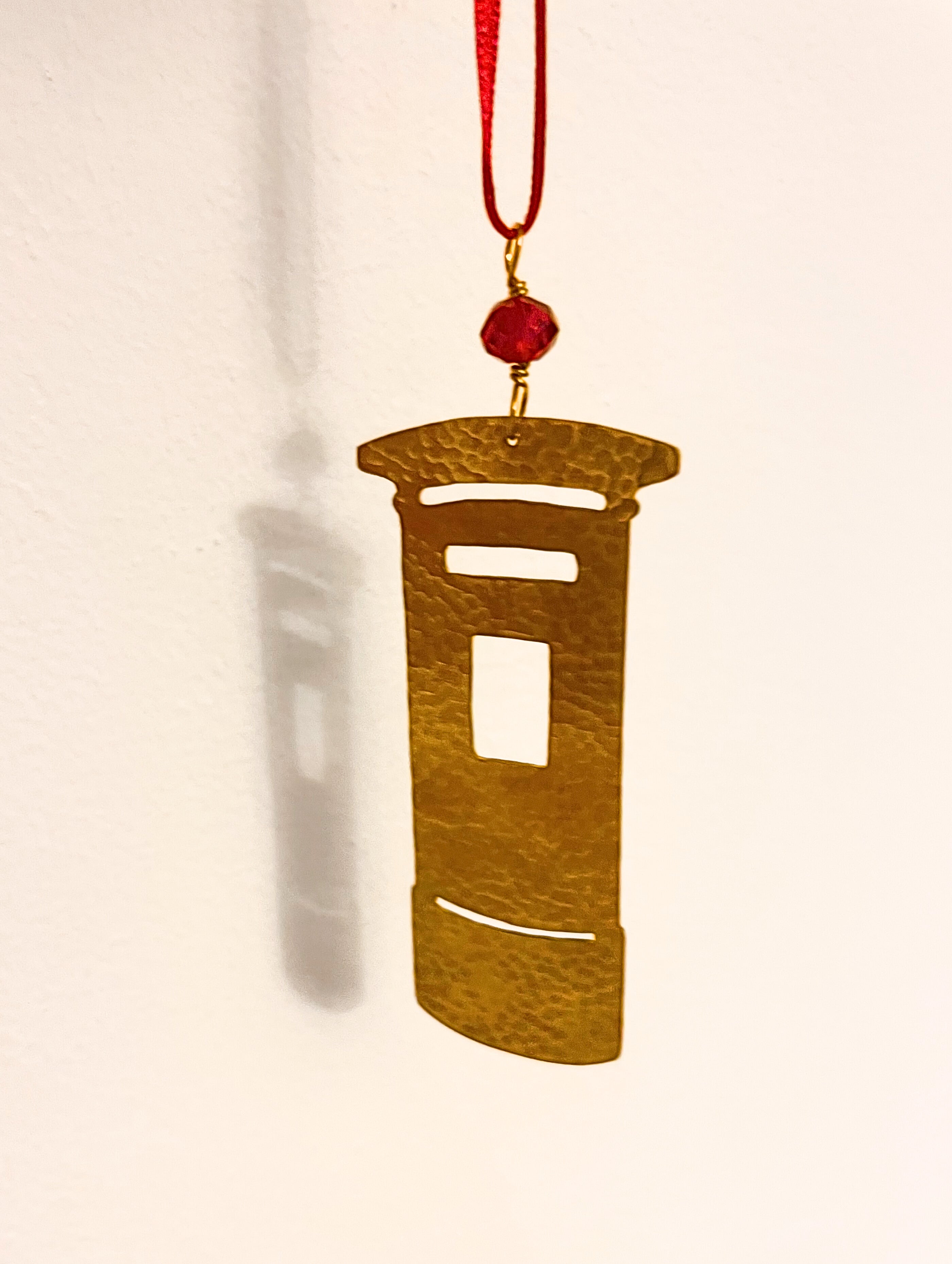 Decorative pendant with a red bead on a beige background
