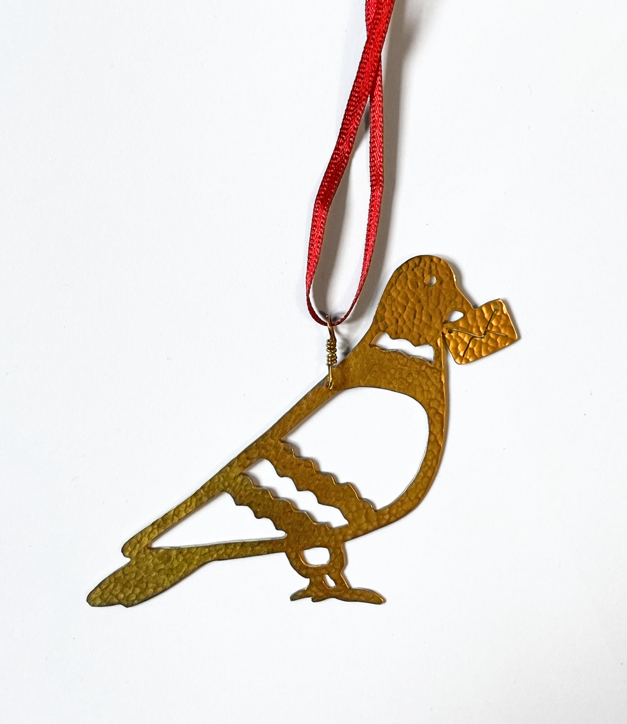 Gold dove-shaped ornament on a red string against a white background
