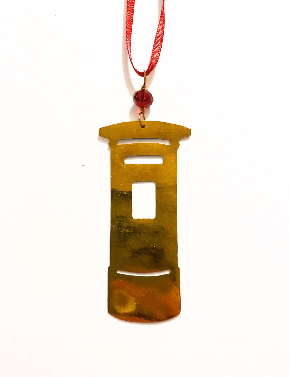 Brass pendant on a red string against a white background