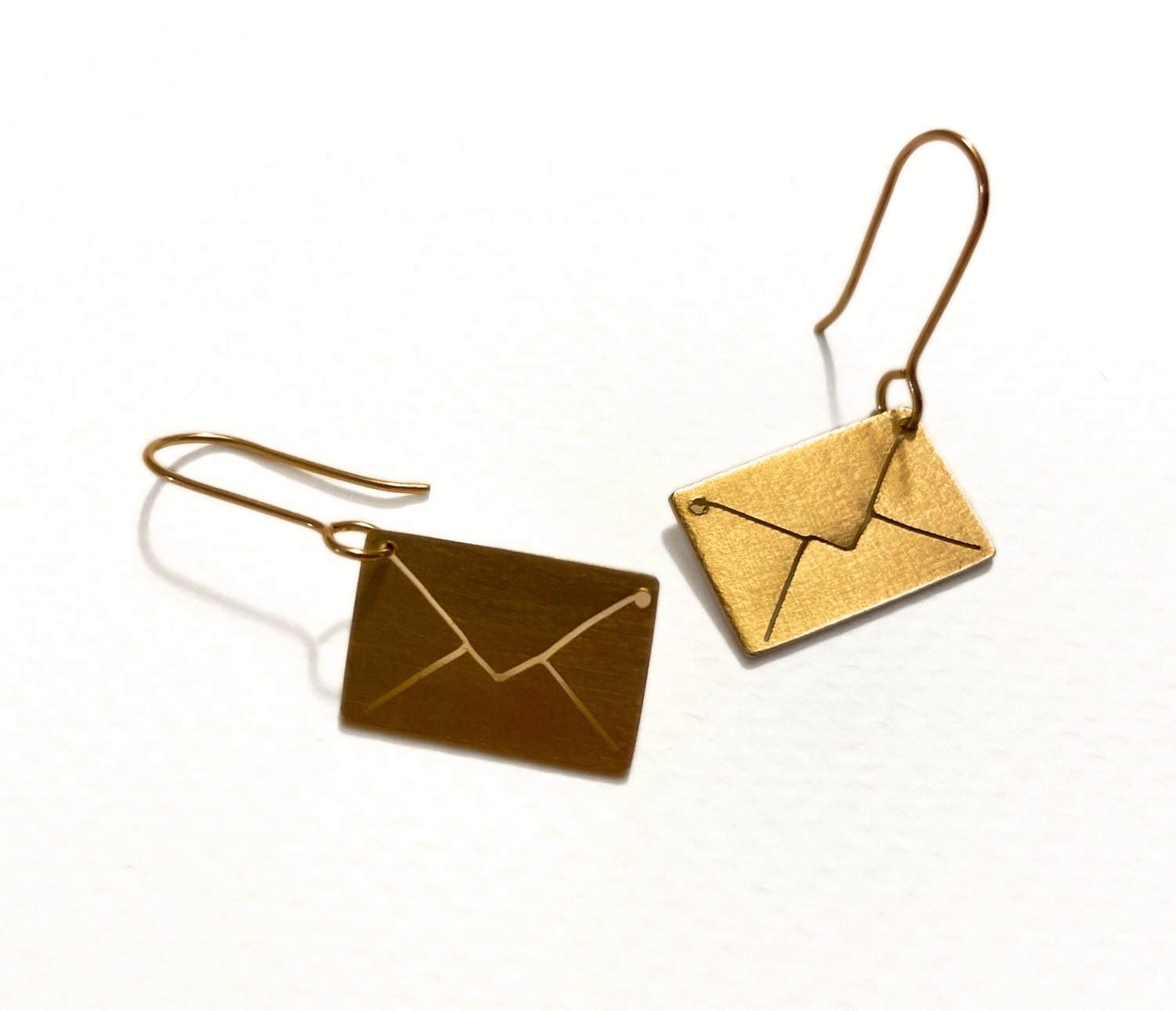 Gold envelope-shaped earrings on a white background