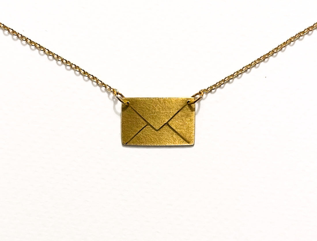 Gold envelope pendant on a chain against a white background