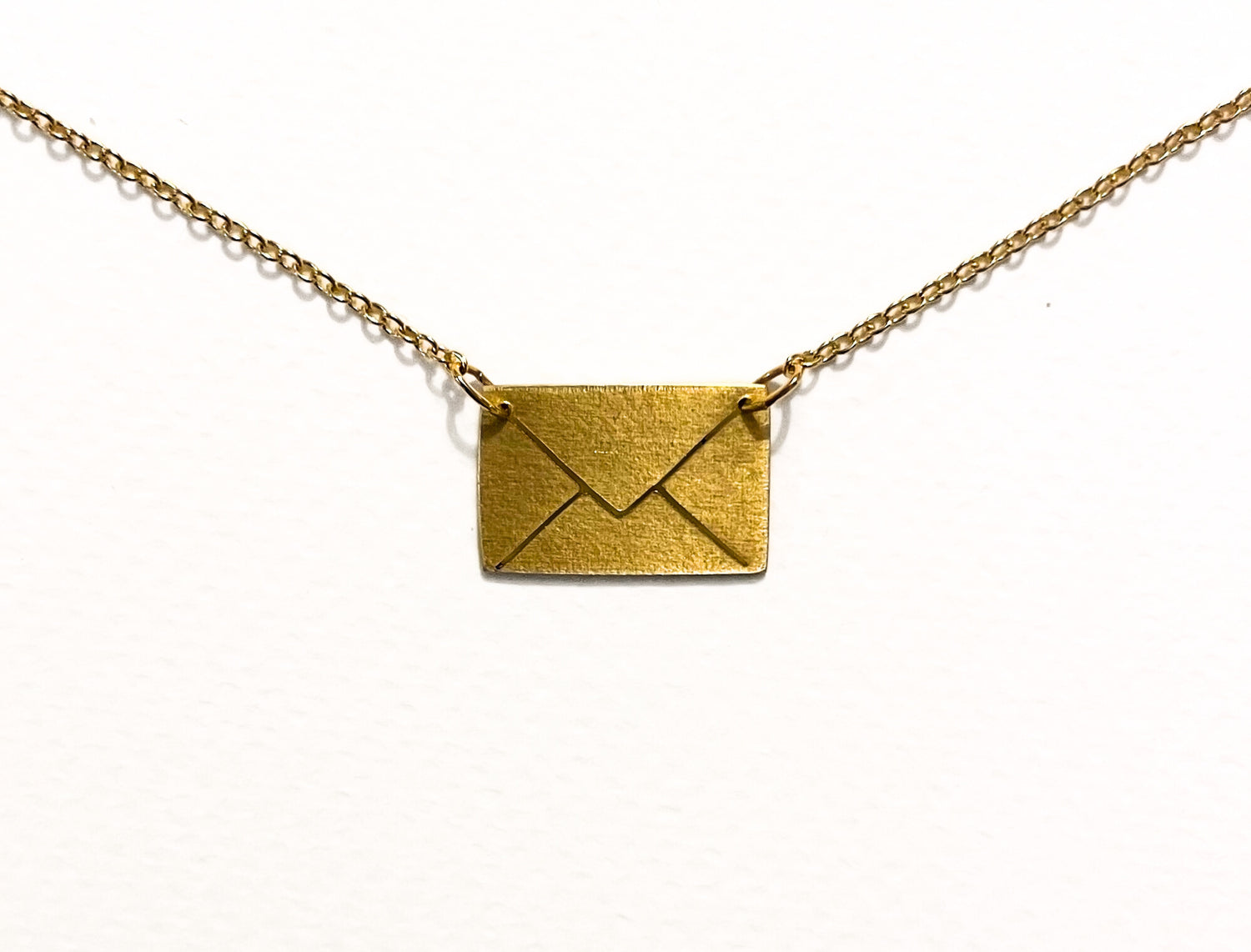 Gold envelope pendant on a chain against a white background