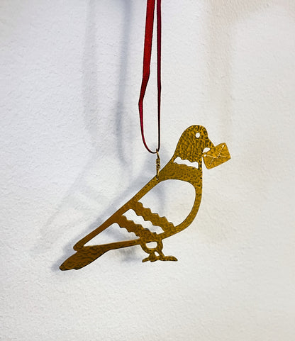 Gold bird-shaped ornament on a red string against a white background