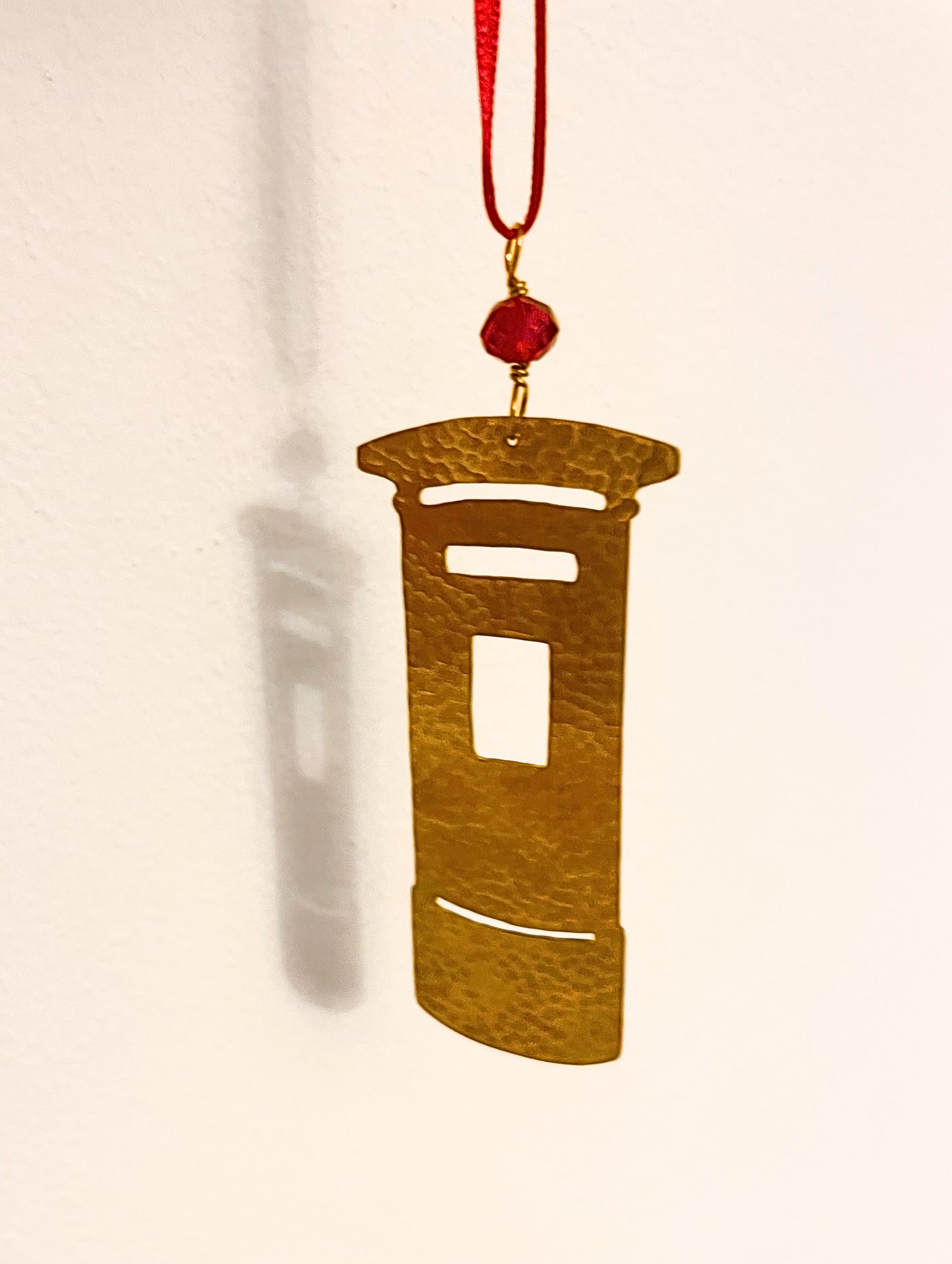Decorative pendant with a red bead on a beige background