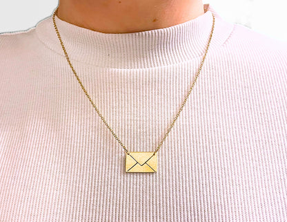 Gold necklace with a square pendant on a light pink sweater