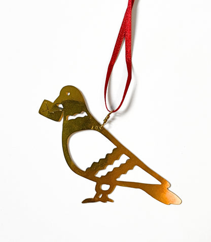 Gold bird-shaped ornament on a red ribbon against a white background