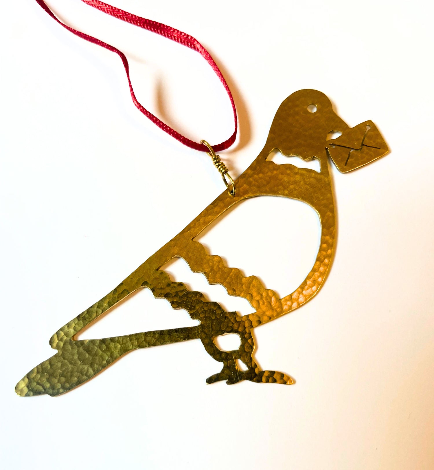 Gold bird-shaped ornament with a red ribbon on a white background