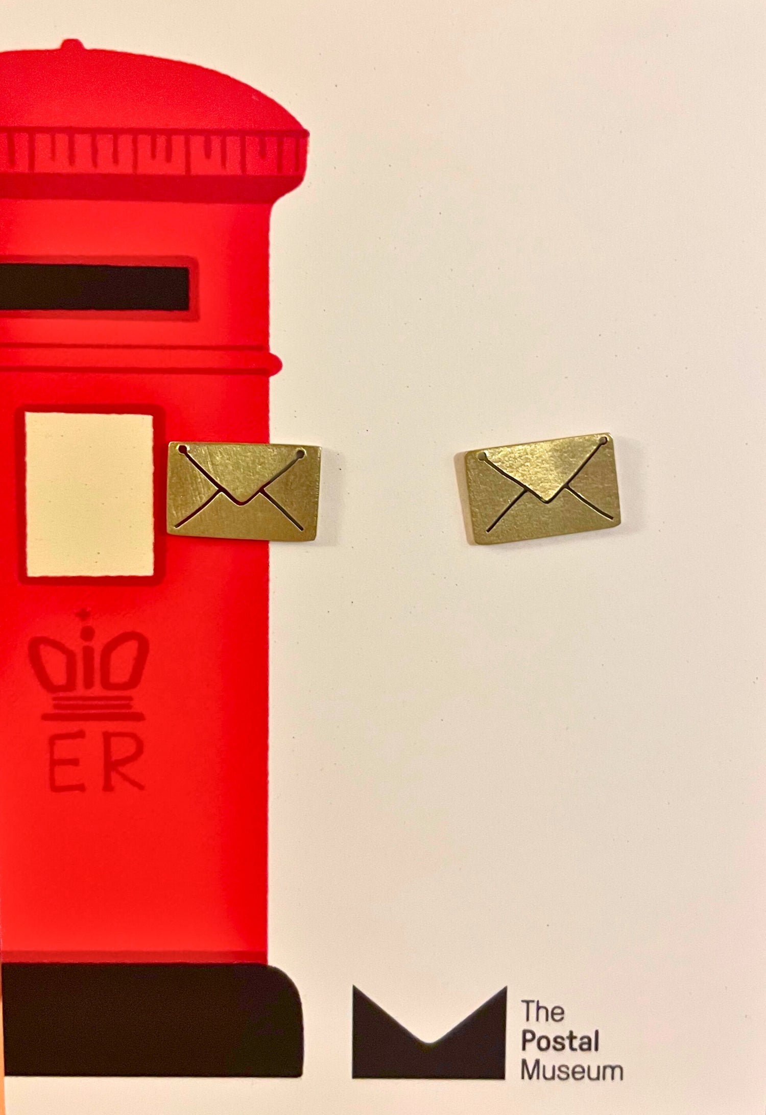 Red mailbox with gold letter boxes on a beige background, featuring &